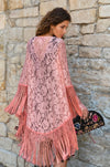 Back view of a pink lace coverup with intricate floral pattern and long fringe detail.
