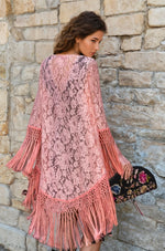 Back view of a pink lace coverup with intricate floral pattern and long fringe detail.
