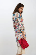 Back view of the same cream printed wrap dress with fringe hem, showing colorful print and 3/4 length sleeves.