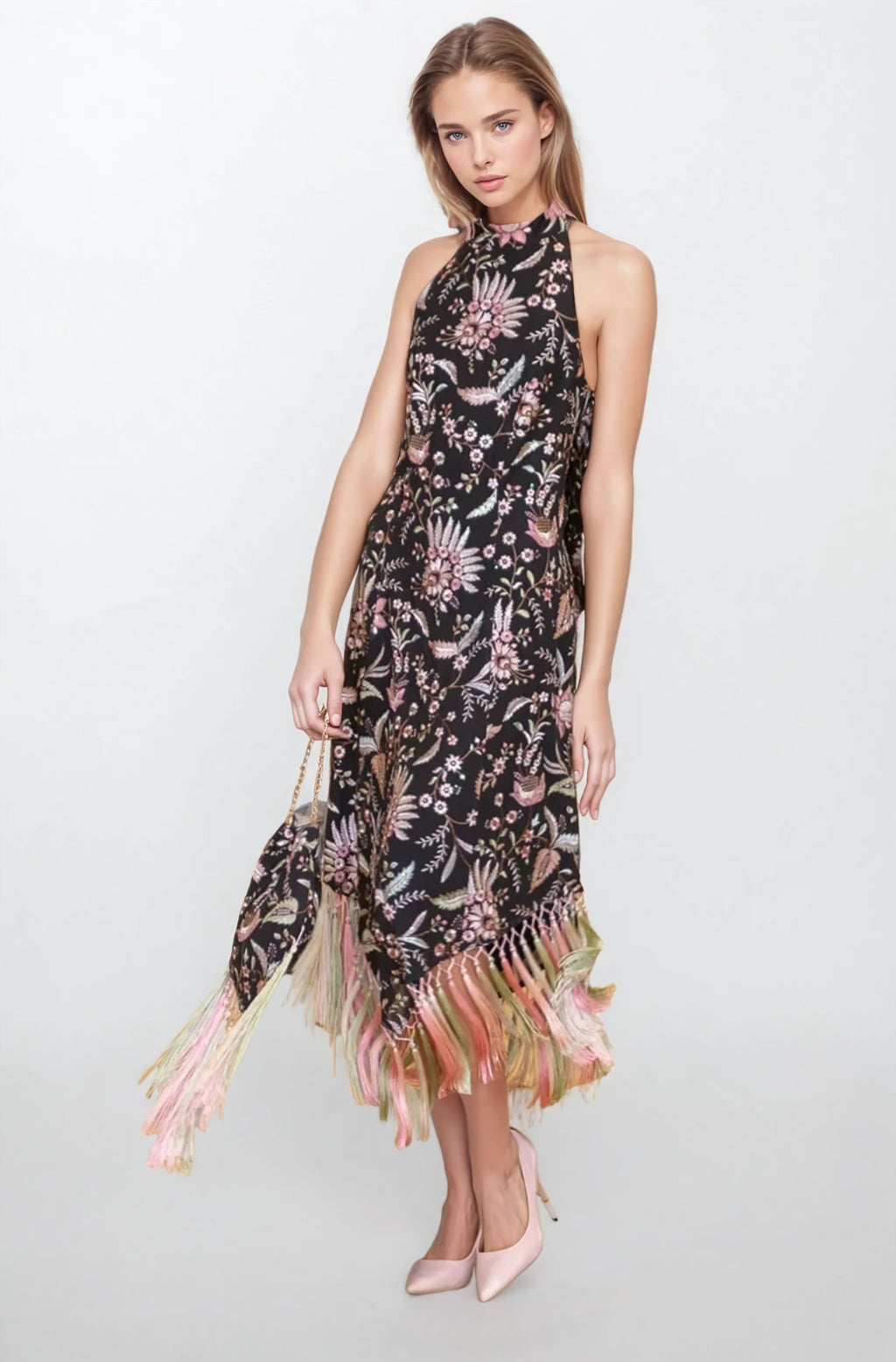 Model wearing a black embroidered halter-neck midi dress with pink and pastel floral motifs and long fringe hem, front view.