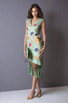 Model wearing a mint green sleeveless midi dress with colorful floral embroidery and long fringe hem, styled with tan heels and a green clutch.