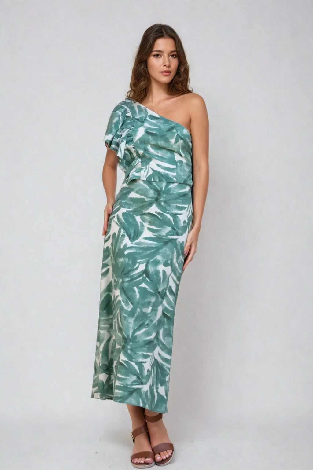 Woman wearing a green leaf print midi skirt with a matching one-shoulder top, standing against a neutral background.