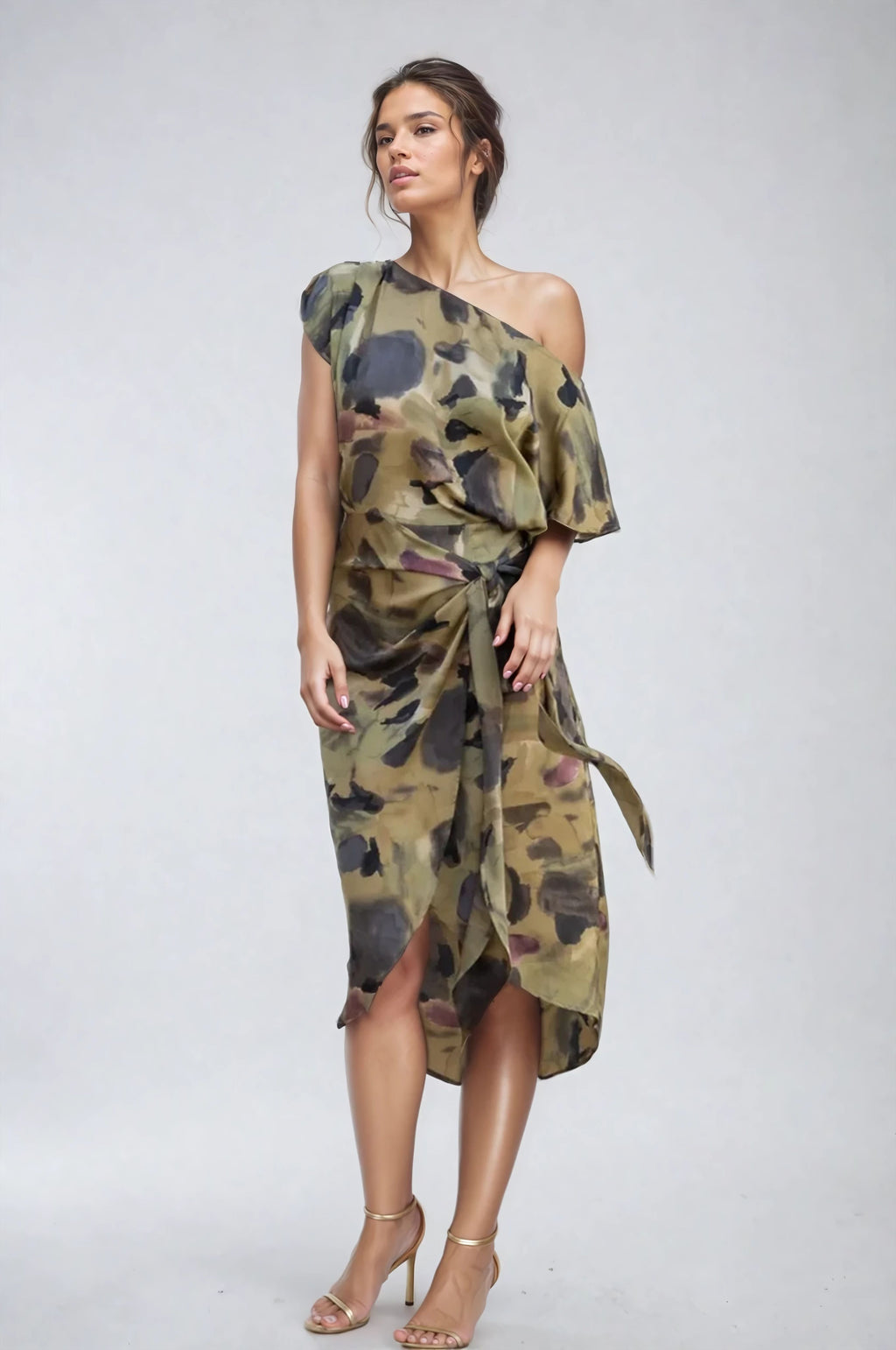 Model wearing one-shoulder olive abstract wrap dress with waist tie, front view.