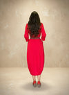 Back view of a woman wearing a red knee-length dress with a braided waist belt, showing the soft drape and flow of the fabric.