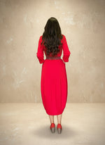 Back view of a woman wearing a red knee-length dress with a braided waist belt, showing the soft drape and flow of the fabric.