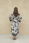 Back view of black toile print dress with kimono sleeves and contrast stripe hem