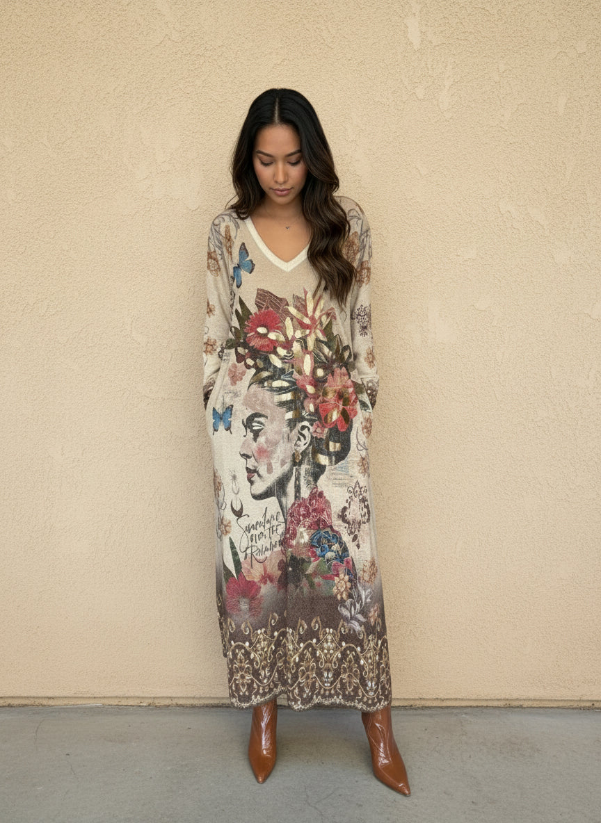 Woman wearing long beige maxi dress with artistic portrait, floral and butterfly print, and bohemian details, styled with brown ankle boots.