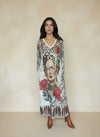 Woman wearing long leopard print maxi dress with artistic face and red floral design on front, styled with brown ankle boots.