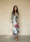 Side view of woman wearing printed leopard and floral maxi dress featuring artistic portrait design, styled with brown boots.