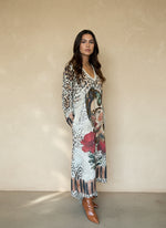 Side view of woman wearing printed leopard and floral maxi dress featuring artistic portrait design, styled with brown boots.