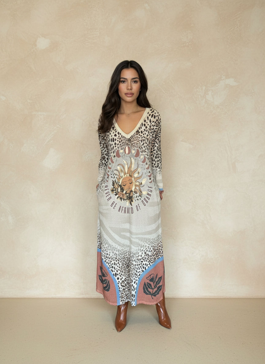 Woman wearing long leopard print maxi dress with sun and moon graphic and the phrase “Never Be Afraid of Change,” styled with brown ankle boots.