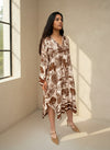 Model wearing brown and cream toile print flowy dress with long sleeves.