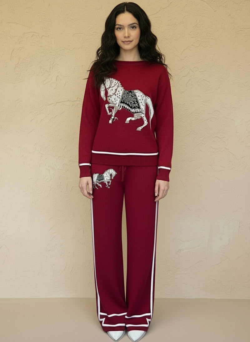 Woman posing in a red embroidered horse knit two-piece outfit with wide-leg pants and white heels.