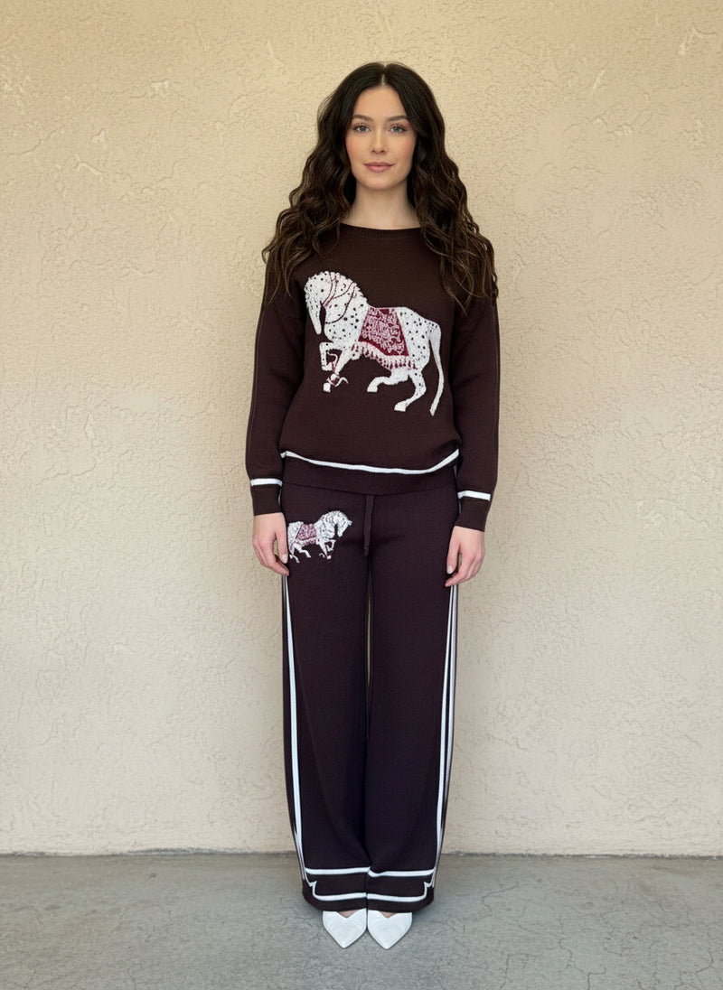 Woman wearing a chocolate-brown knit two-piece set with white and red horse embroidery and striped trim.