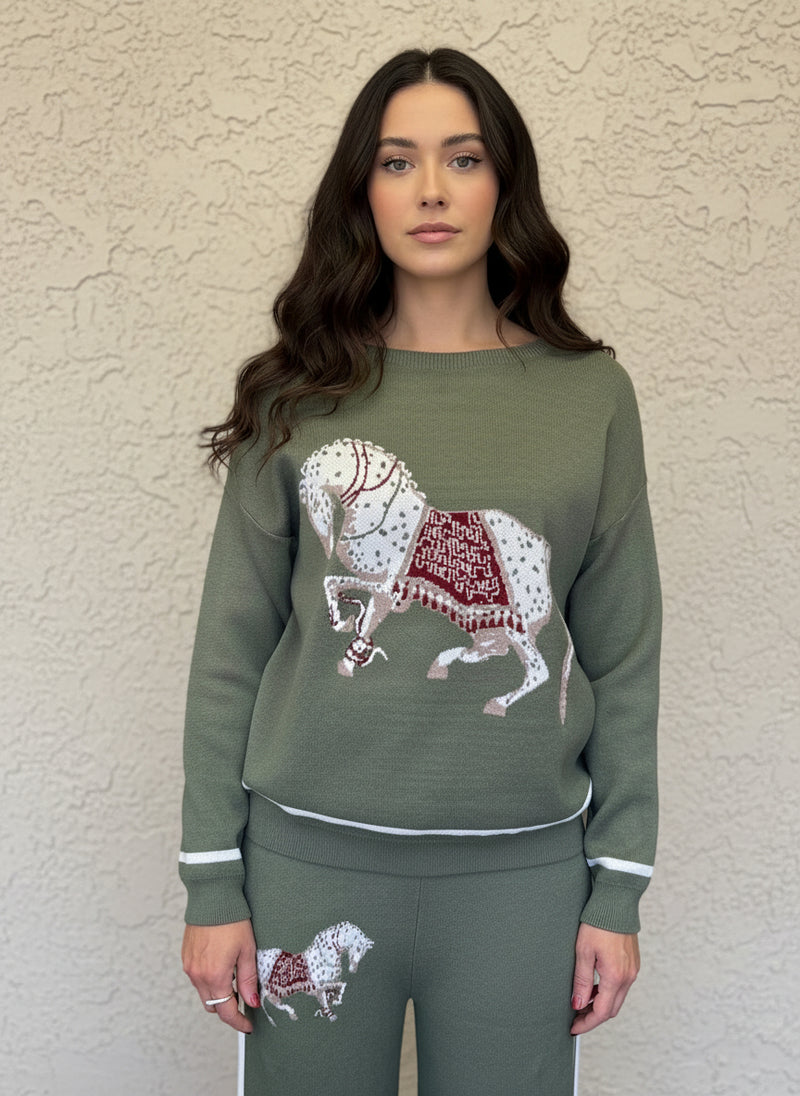 Close-up of olive-green horse-print knit sweater featuring a white and red ornate horse design.