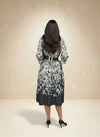 Back view of a woman in a belted black and white floral midi dress — elegant botanical print outfit with flowy skirt.