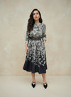 Woman standing front-facing in a black floral print dress with long sleeves and belt — chic floral pattern midi dress for women.