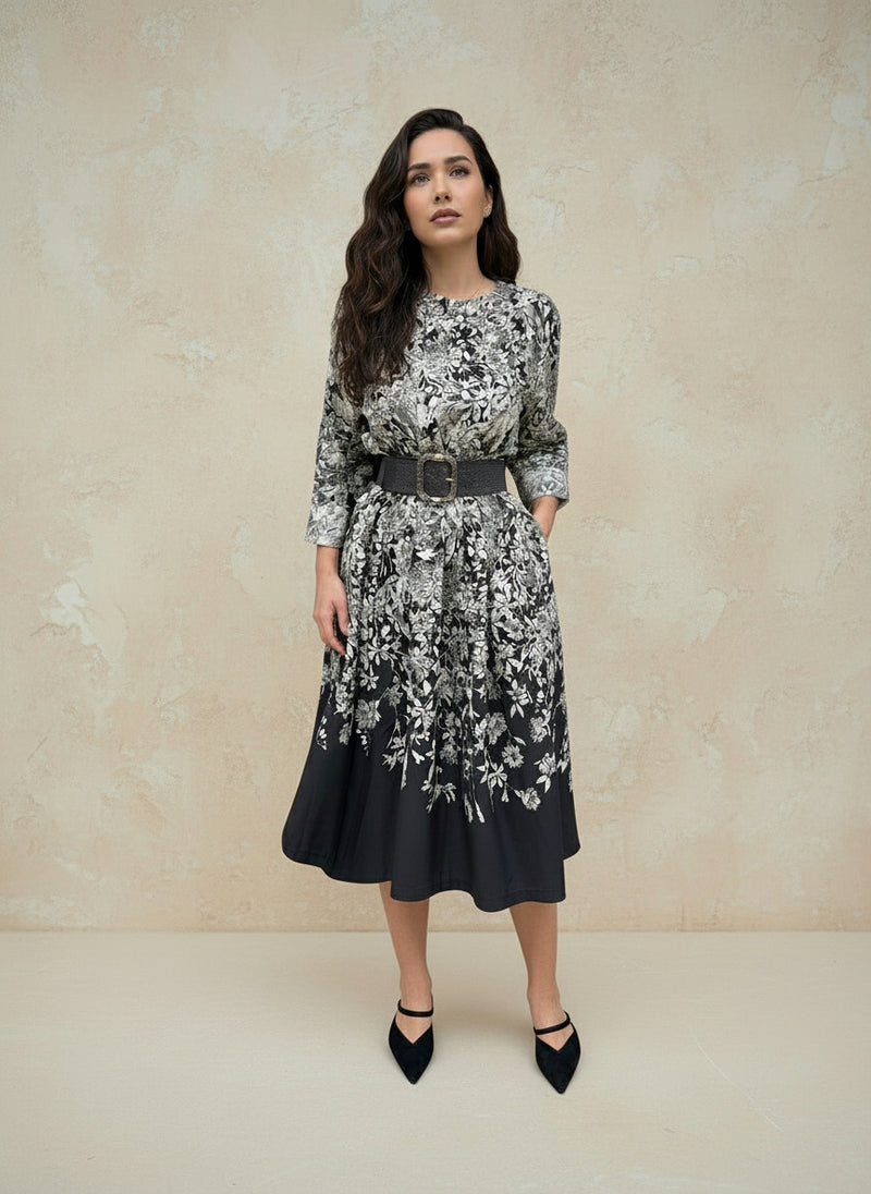 Woman standing front-facing in a black floral print dress with long sleeves and belt — chic floral pattern midi dress for women.