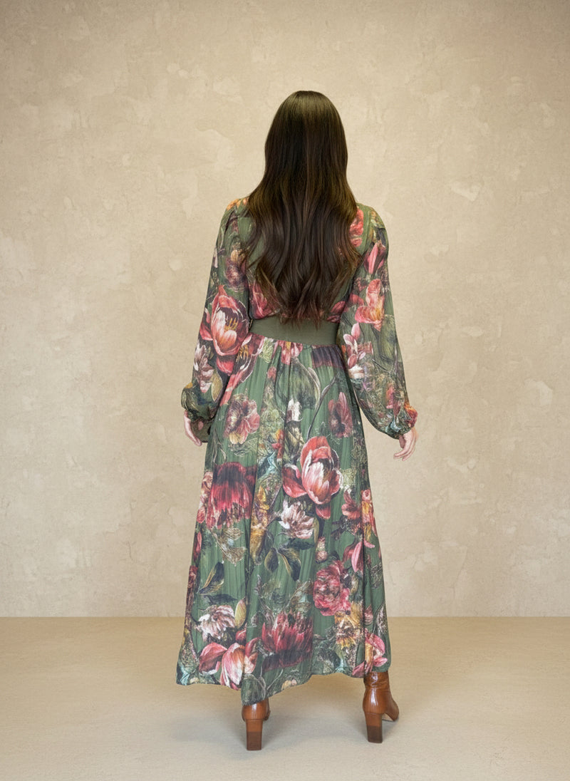 Back view of a woman in a green floral maxi dress with long sleeves and a green belt, featuring a vintage-inspired botanical print.