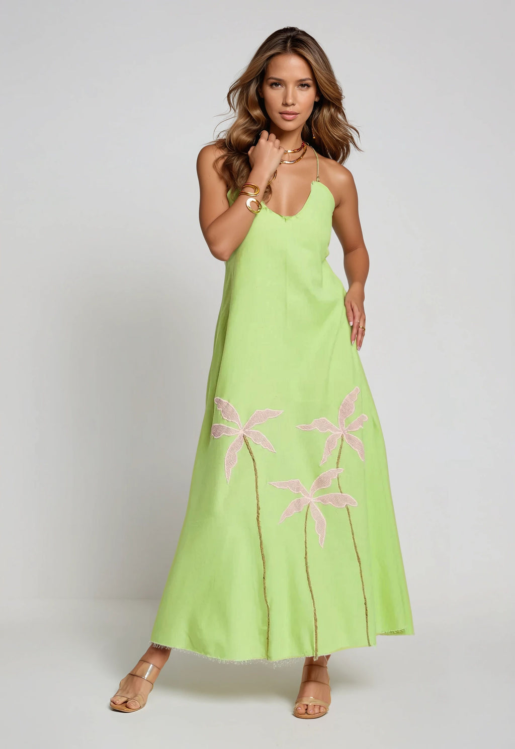 Woman modeling a lime green cotton maxi dress with pink palm embroidery and delicate gold jewelry.