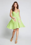 Woman wearing a sleeveless lime green cotton mini dress with a halter neckline and light pink palm tree embroidery. The dress has a relaxed A-line silhouette and frayed hem.