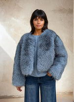 Close-up of a model in a sky-blue faux fur coat showing the soft fluffy texture and casual winter outfit.