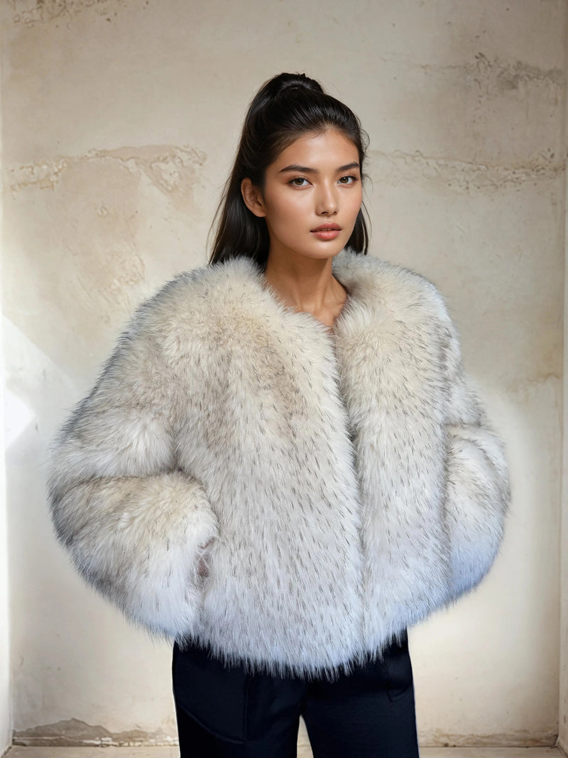 Woman dressed in a soft white faux fur jacket with subtle grey accents, standing in front of a minimalist beige background. Her dark hair is styled in a high ponytail, creating a clean, modern, and sophisticated winter outfit aesthetic.