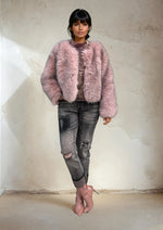 Casual street style outfit with a pastel pink faux fur coat and ripped jeans for winter fashion inspiration.