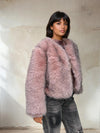Fashion model in a mauve pink faux fur jacket showing cozy winter outerwear with soft voluminous texture.