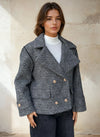 Woman wearing textured grey double-breasted peacoat with gold buttons.