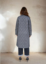 Model in a gray double-breasted checkered wool coat with gold buttons, styled with rolled-up jeans and black pointed heels for minimalist winter fashion