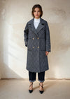 Model in a black gray double-breasted checkered wool coat with gold buttons, styled with rolled-up jeans and black pointed heels for minimalist winter fashion