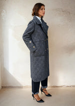 Model in a gray double-breasted checkered wool coat with gold buttons, styled with rolled-up jeans and black pointed heels for minimalist winter fashion