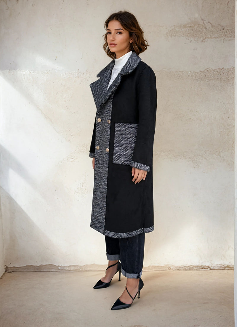 Model showcasing a black and gray contrast double-breasted coat with oversized lapels and gold buttons, styled with cuffed denim and black heels.
