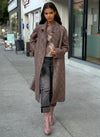 Model wearing a long brown textured wool coat with gold buttons, paired with distressed gray jeans and pink patent ankle boots, styled for fall street fashion