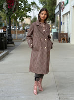 Model wearing a long brown textured wool coat with gold buttons, paired with distressed gray jeans and pink patent ankle boots, styled for fall street fashion