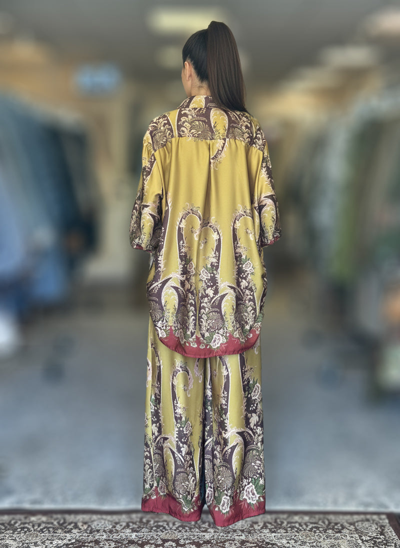 Back view of a chartreuse silk baroque print co-ord set with maroon border details. Oversized shirt and matching wide-leg trousers in opulent design.