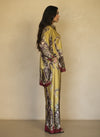Model in chartreuse yellow silk matching set with intricate burgundy and olive baroque prints, featuring a relaxed shirt and flowy pants. Luxury loungewear with a bold statement look.