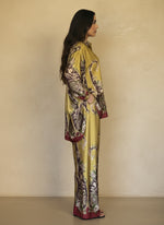 Model in chartreuse yellow silk matching set with intricate burgundy and olive baroque prints, featuring a relaxed shirt and flowy pants. Luxury loungewear with a bold statement look.
