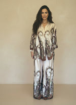 Model wearing a cream satin baroque print coordinated set featuring floral brown motifs and relaxed wide-leg pants. Elegant high-end women’s loungewear look.