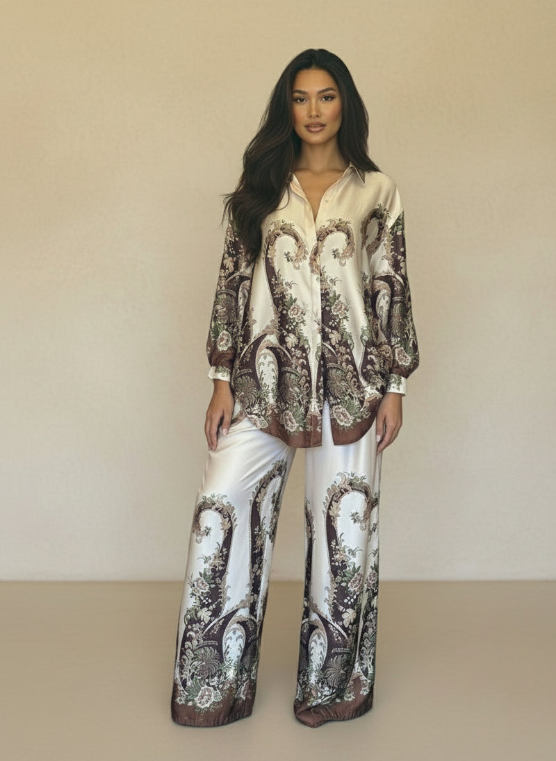 Model wearing a cream satin baroque print coordinated set featuring floral brown motifs and relaxed wide-leg pants. Elegant high-end women’s loungewear look.