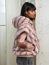 Back view of a woman modeling a blue faux fur sleeveless hoodie showing the chevron fur pattern and hood shape under natural light.