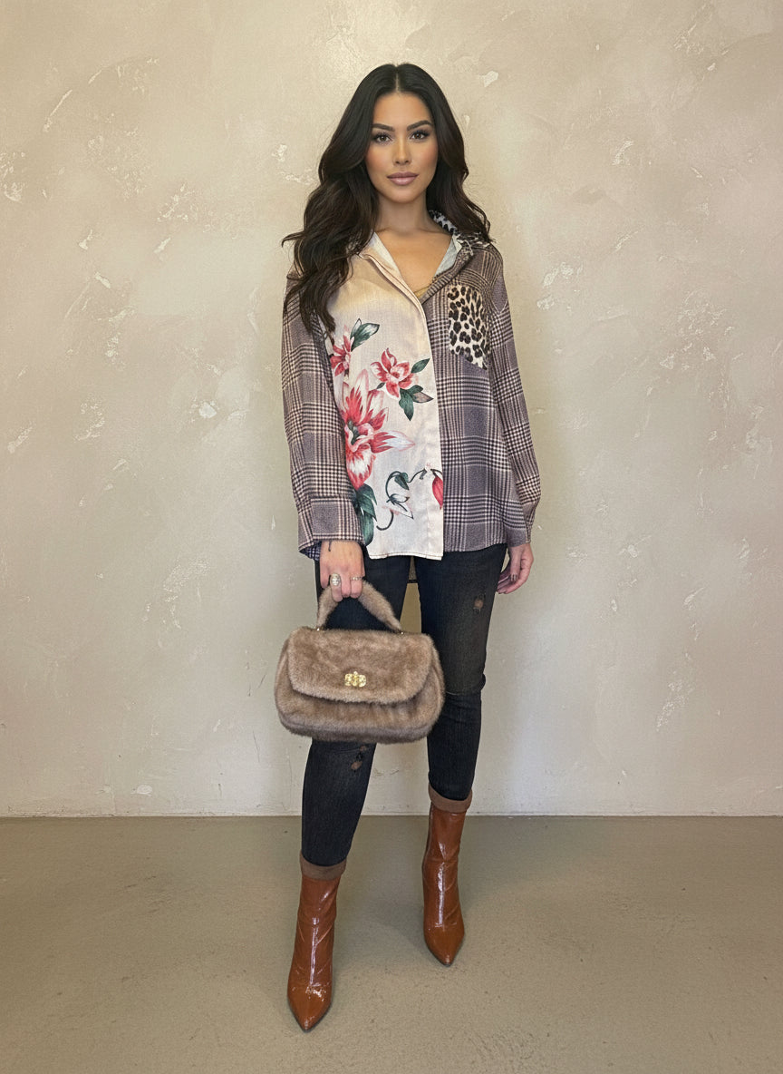 Model styled in a plaid floral and leopard print button-up blouse, paired with black skinny jeans, brown ankle boots, and a tan faux fur handbag, posing indoors.