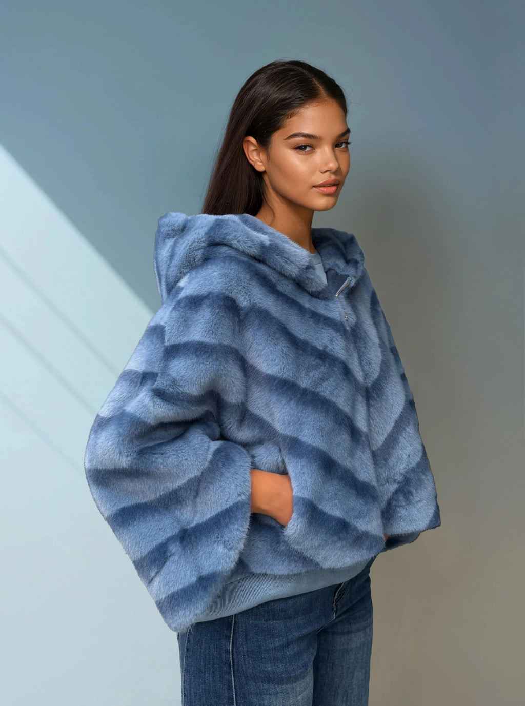 Model wearing luxurious light blue faux fur hooded jacket with diagonal stripe texture — elegant winter fashion. 
