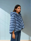 Side view of woman in soft blue hooded faux fur coat paired with denim jeans — cozy and stylish winter outfit.