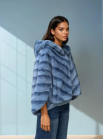 Side view of woman in soft blue hooded faux fur coat paired with denim jeans — cozy and stylish winter outfit.