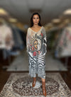Front view of woman wearing celestial sun and moon print maxi dress with red roses and zebra patterns, paired with brown heeled boots.