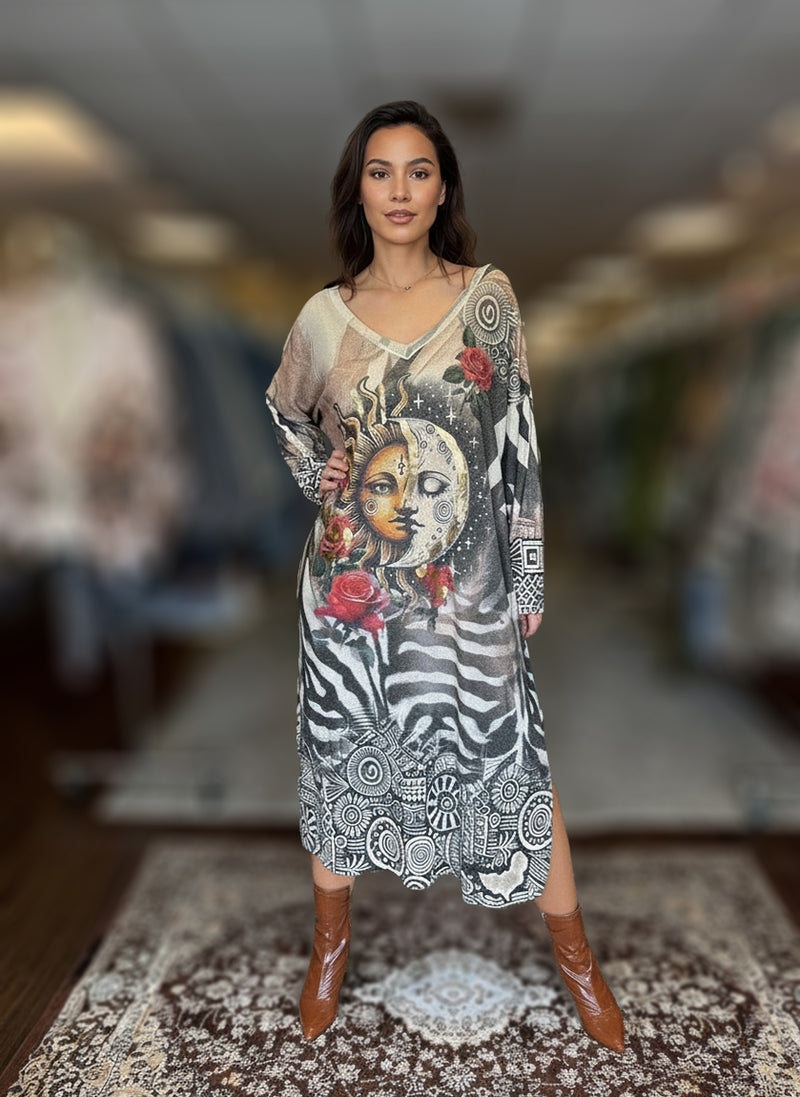 Woman posing in long boho-inspired maxi dress featuring artistic sun and moon graphic, red floral accents, and zebra pattern, styled with brown ankle boots.