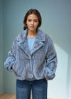 Model wearing a light blue ribbed faux fur jacket with wide collar and relaxed fit, styled with denim jeans against a minimal background.