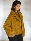 Side view of woman in mustard yellow textured fur jacket, showcasing oversized sleeves and soft velvet finish